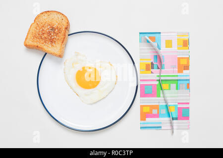 Ei gebraten in einem Herzen - auf einem Teller mit Toast Draufsicht mit Schatten auf weißem Hintergrund geformt Stockfoto