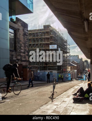 GLASGOW, Schottland - 2. NOVEMBER 2018: ein Schüler gehen zu klassifizieren, während Arbeiter auf der Website von Glasgow School of Art arbeiten Stockfoto