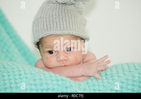 4 Wochen alt neugeborenes Baby Boy mit grauen Hut auf grüne Decke Stockfoto