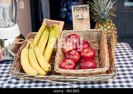 Frische Apfel, Banane und Ananas in einem Korb und ein Mixer auf der Theke von outdoor Saft bar. Preis tags sind in französischer Sprache. Stockfoto