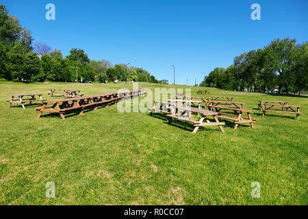 Holz- Picknick Tische auf der grünen Wiese Feld in den Park an einem sonnigen Sommertag Stockfoto