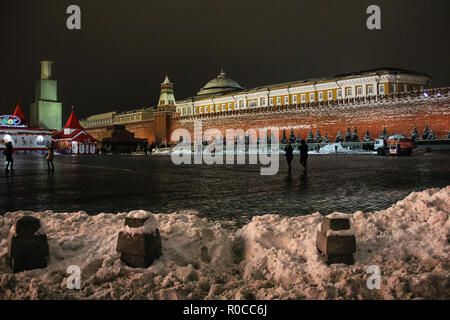 Moskau, Russland - Dezember 2014: Wiederaufbau des Spasskaja Turm im Gerüst auf dem Roten Platz im Winter. Die Menschen wandern in der Nacht in der Nähe von Schneeverwehungen, Eis Stockfoto