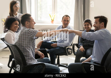 Die männlichen Kollegen Faust stoßen bei Treffen der Gruppe feiern Gute t Stockfoto
