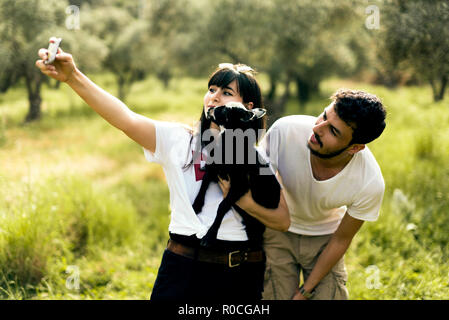 Kaukasische weiße Junge Frau und einem kaukasischen weißen jungen Mann eine takşng selfie mit einem goatling auf der Wiese. Stockfoto