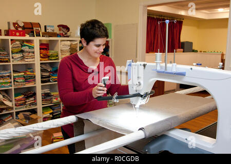 Lächelnde Person arbeitet an einem langen Arm Nähmaschine in Ihrem Studio Stockfoto