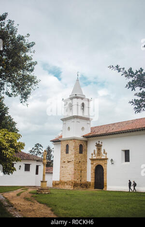 Zwei lokalen Jungen gehen Sie in Richtung der Iglesia Nuestra Señora del Rosario, einem weißen Katholische Kirche im Zentrum von Villa de Leyva, einer kleinen Stadt in Kolumbien Stockfoto