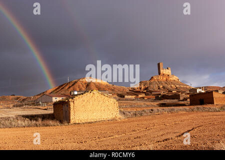 Regenbogen über einem ländlichen kastilischen Dorf mit einer Ruine Burg in Montuenga de Soria, Castilla la Mancha, Spanien Stockfoto