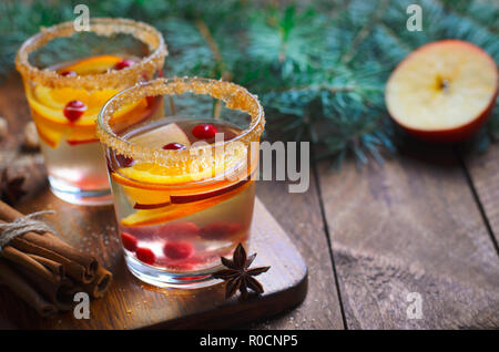 Winter Cocktail, Weihnachten Sangria mit Apfelscheiben, Orange, Cranberry und Zimt, erfrischendes Getränk auf Holz- Hintergrund Stockfoto