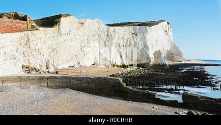 Anzeigen von Seaford Richtung splash Point, East Sussex. England, Felsen, Meer und blauem Himmel, gebrochene groyne, mit Blick auf die Überreste der Cliff Cottage Stockfoto