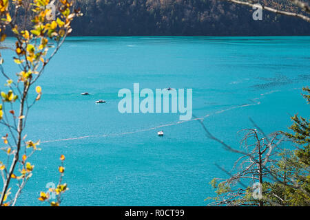 Blick vom Weg rund um den Alpsee, Schwangau, Deutschland, an der türkisfarbenen See mit Tretbooten, an einem warmen sonnigen Tag im Herbst. Stockfoto