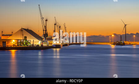 Boote auf einem Wharf in einem industriellen Hafen während einer farbenfrohen Sonnenuntergang Stockfoto