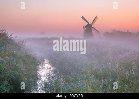 Polderlandschaft mit charakteristischen traditionelle Windmühle an einem nebligen Septembermorgen in den Niederlanden Stockfoto