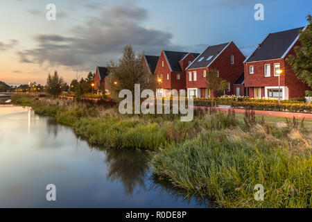 Langzeitbelichtung Nacht geschossen von einer Straße mit modernen ökologischen Mittelklasse Familie Häuser mit umweltfreundlichen River Bank in Veenendaal, Niederlande. Stockfoto