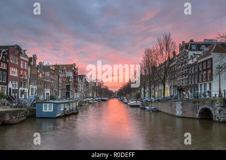 Farbenfroher Sonnenuntergang über Herengracht mit Haus Boot und traditionellen Grachtenhäuser in das UNESCO-Weltkulturerbe von Amsterdam Stockfoto