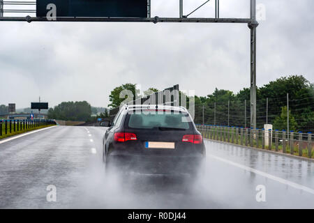 Ein Auto auf nasser Straße im Regen. Ansicht von hinten durch das Fenster. Stockfoto