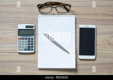 Flach foto Büro Schreibtisch mit Smartphone, Notebook, Rechner, Silber pen und Gläser. Holztisch, Ansicht von oben. Selektive konzentrieren. Stockfoto