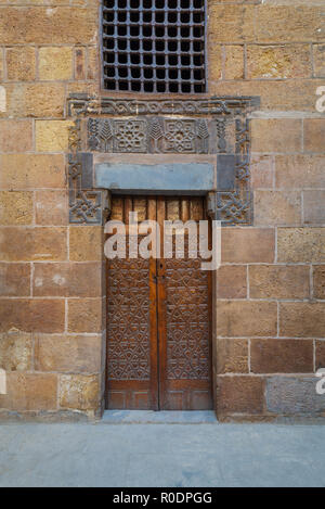 Holz verzierten Tür mit geometrischen eingravierte Muster auf externen Stil der alten Ziegel Steinmauer, Kairo, Ägypten Stockfoto