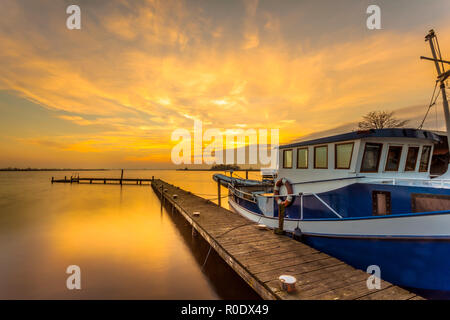Boot auf einem Steg in den See während der schönen orange Sonnenuntergang Stockfoto