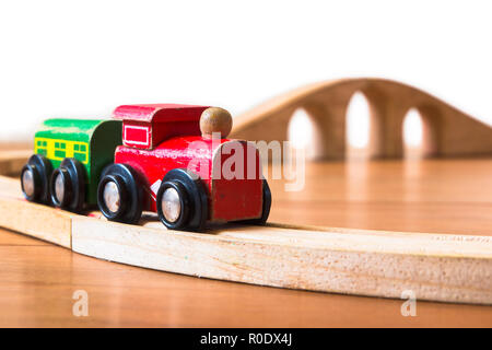 Hölzerne Spielzeugeisenbahn auf die Bahn mit Brücke im Hintergrund Stockfoto