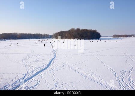 Winter Szene. Fishermans fangen Fische im Fluss auf der Eisfläche mit Schnee Stockfoto