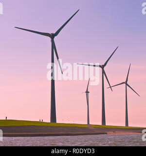 Giant 3 Megawatt Windenergieanlagen entlang der Deich in die Niederlande vom Wasser aus gesehen Stockfoto