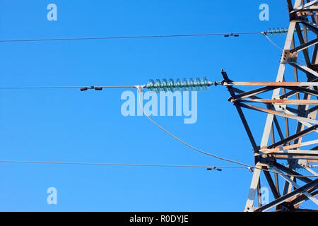 Isolatoren, Drähte und Fragment aus Metall elektrische Turm auf dem Hintergrund des blauen Himmels Stockfoto