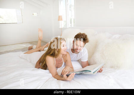 Mid-Adult Paar Verlegung auf Bett und liest ein Buch Stockfoto