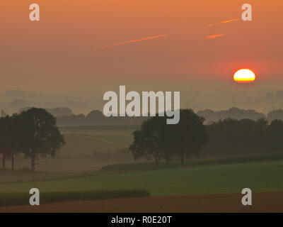 Die sunis steigt über Misty, hügeliges Ackerland Stockfoto