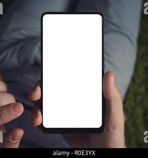Nahaufnahme von einem jungen Mann, der lange Holding Smartphone mit dem weißen Bildschirm. Person ist on-line von einem Smartphone. Nahaufnahme von einem Mann mit der cellp Stockfoto