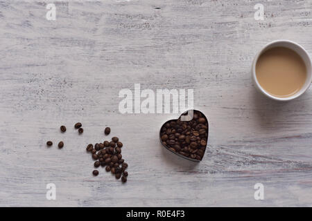 Cup op Kaffee und Herzform geröstete Kaffeebohnen auf weißem rustikalen Holztisch/Romantisch still life Food Design Stockfoto