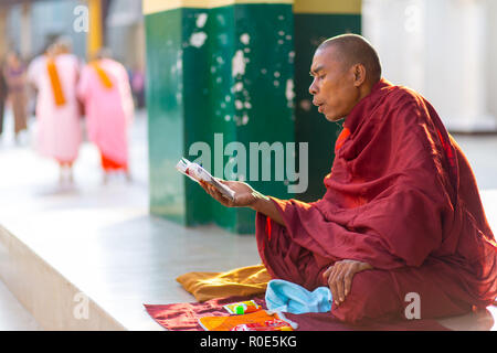 Rangun, Myanmar - 18. JANUAR 2017: Eine burmesische Mönch ist Lesen und Singen der heiligen Schriften des Buddhismus die Shwedagon-Pagode in Rangun (Yangon), Mya Stockfoto