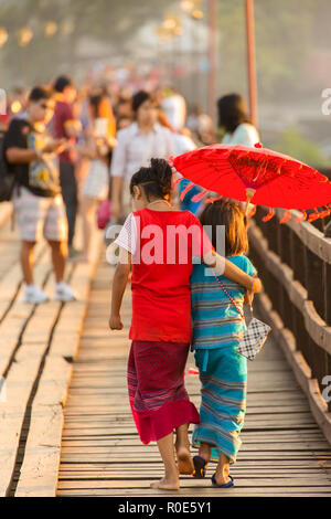 SANGHLABURI, Thailand, 23. JANUAR 2016: Zwei Thais kleine Mädchen umarmt und laufen auf dem Mon Brücke, mit einem Regenschirm, Sangkhlaburi, Thailan Stockfoto