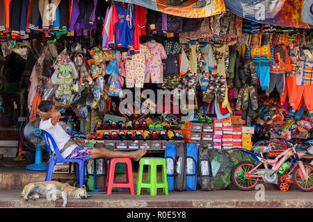 THONG PHA PHUM, Thailand, 23. Januar 2016: Ein Mann und sein Hund liegen schlafend unter der schweren Sonne in der Straße Kleidung Store in Thon Pha Phum, Thai Stockfoto