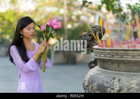 Vietnamesisches Mädchen im Buddhistischen Tempel beten, holding Lotus Blumen, Saigon, Vietnam Stockfoto