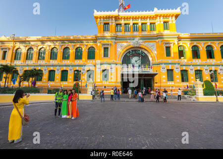 HO CHI MINH, Vietnam, 25. Februar 2015: Große Ansicht auf der zentralen Französischen Kolonialstil Post mit vietnamesischen Mädchen in traditionellen Ao Dai dres Stockfoto