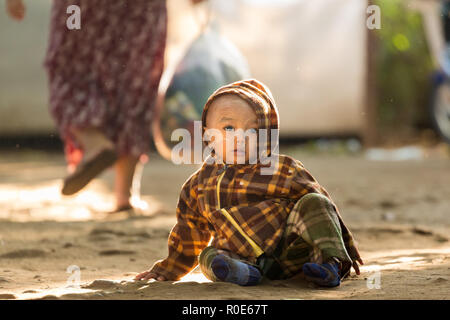 BAGAN, Myanmar, 24. JANUAR 2015: Eine burmesische Kind sitzt in einem dreckigen Straße des alten Bagan in Myanmar (Birma) Stockfoto