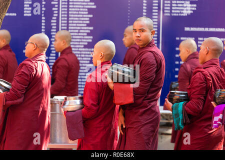 AMARAPURA, Myanmar, 20. JANUAR 2015: Mönche sind queuing Holding ihren Schüsseln die einmalige tägliche Mahlzeit am Mittag im Kloster Mahagandayon n Sammeln Stockfoto