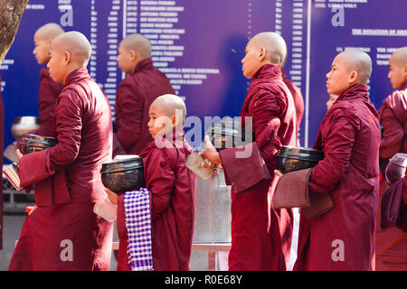 AMARAPURA, Myanmar, Januar 20, 2015: Junge Mönche sind queuing Holding ihren Schüsseln die einmalige tägliche Mahlzeit am Mittag in der mahagandayon monast sammeln Stockfoto