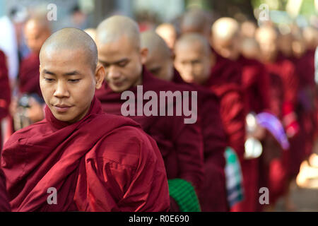 AMARAPURA, Myanmar, Januar 20, 2015: Junge Mönche sind queuing Holding ihren Schüsseln die einmalige tägliche Mahlzeit am Mittag in der mahagandayon Monas sammeln Stockfoto