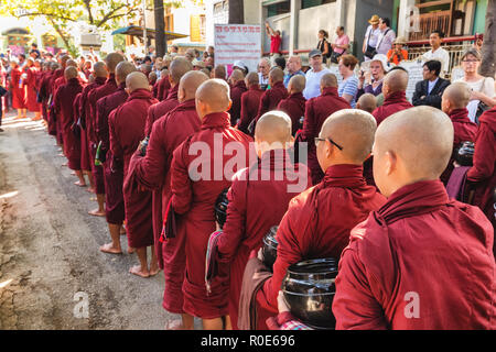 AMARAPURA, Myanmar, Januar 20, 2015: Junge Mönche sind queuing Holding ihren Schüsseln die einmalige tägliche Mahlzeit am Mittag in der mahagandayon Monas sammeln Stockfoto