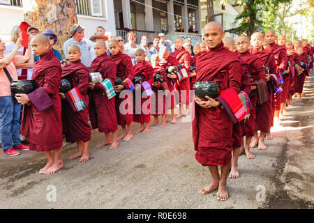 AMARAPURA, Myanmar, Januar 20, 2015: Junge Mönche sind queuing Holding ihren Schüsseln die einmalige tägliche Mahlzeit am Mittag in der mahagandayon monast sammeln Stockfoto