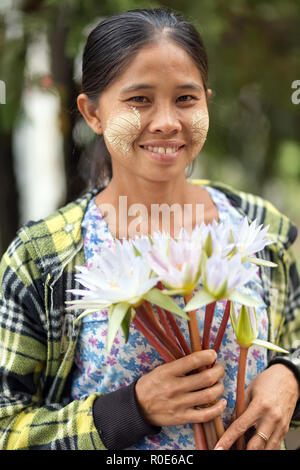 MANDALAY, Myanmar, 17. JANUAR 2015: Porträt einer Frau mit thanaka Pulver Lamellenmuster, Verkauf von waterlily Blumen am Eingang der Pagode Kut Stockfoto