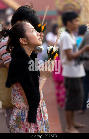 LAMPHUN, Thailand, 31. Dezember 2014: einer Frau mit Räucherstäbchen und Blumen ist das Beten für das neue Jahr außerhalb des buddhistischen Tempel von Wa Stockfoto