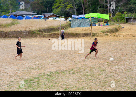 MAE KLANG Luang, Thailand, 31. Dezember 2014: Einige Kinder spielen Fußball-Fußball in einem trockenen geerntet Reis Feld im Dorf von Mae Klang Luang, Stockfoto