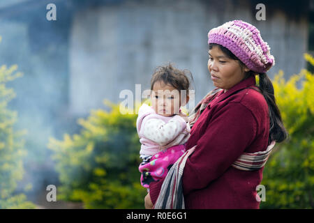 MAE KLANG Luang, Thailand, Dezember 31, 2014: Ein freundliches Karen Frau in traditioneller Kleidung hält Ihr Kind im Dorf Mae Klang Luang Stockfoto