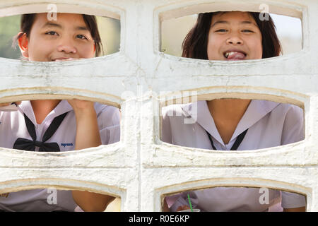 PHANG NGA, Thailand, 27. Januar: Thai Mädchen, die traditionelle Schule Kleid sind fröhlich Posieren hinter einem Beton Zaun in Phang Nga Village, Thail Stockfoto