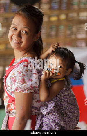 PHANG MAPHA, Thailand, 19. November 2012: eine Mutter von einem Karen ist mit ihrer Tochter auf dem Rücken, in ein Tuch gewickelt, phang Mapha (Soppong) Stockfoto