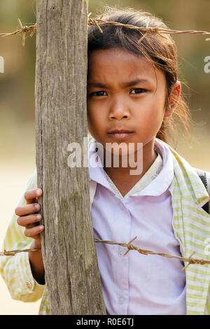 SAYABURY, Laos, 16. Februar 2012: Laotischen kleines Mädchen in der Nähe von einem Zaun Pole auf dem Schulhof während der Elefantasia Festival in Sayaboury, Laos posing Stockfoto