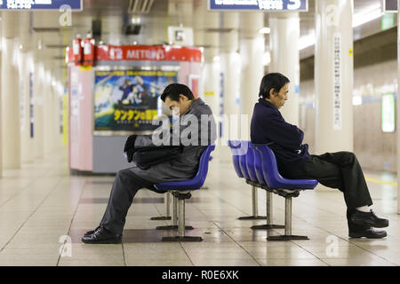 Tokio, Japan, 30. November: Zwei nicht identifizierte japanische Männer schlafen in der Nähe der U-Bahn warten auf die Bahn zu kommen, am frühen Morgen in Tokio, Japan, auf Novem Stockfoto