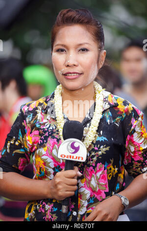 BANGKOK, THAILAND, 13. APRIL 2011: Ein TV-Reporter Frau Reden halten Ihr Mikrofon in der Silom Road über die Songkran buddhistische Festivals in Ba Stockfoto